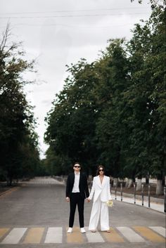 a man and woman walking across a cross walk holding hands