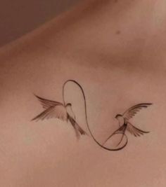 the back of a woman's chest with two birds flying around it and an arrow on