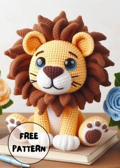 a crocheted stuffed lion sitting on top of a book next to flowers and a pen