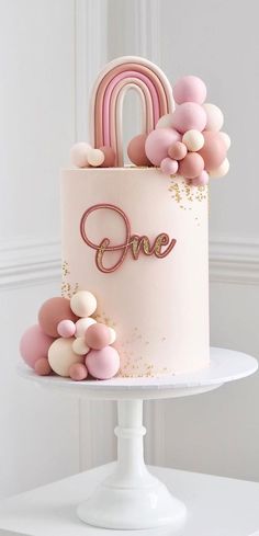 a pink and gold cake with balloons on top