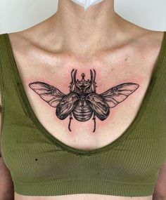 a woman's chest with a black and grey bee tattoo on her left side