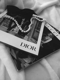 two necklaces are laying on top of a magazine with the word dior printed on it