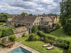 an aerial view of a house with a swimming pool in the foreground and lush greenery surrounding it