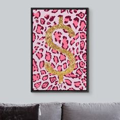 a pink and gold leopard print with a dollar sign on it's side in front of a gray couch