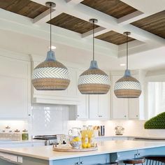 three lights hanging from the ceiling in a kitchen with white cabinets and blue stools