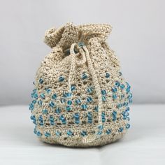 a crocheted bag with blue beads on the front and bottom, sitting on a white surface