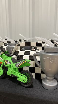 a green toy motorcycle sitting on top of a black and white checkered table