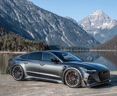 a grey car parked in front of a mountain lake