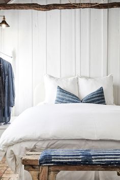 a bed with white linens and blue pillows