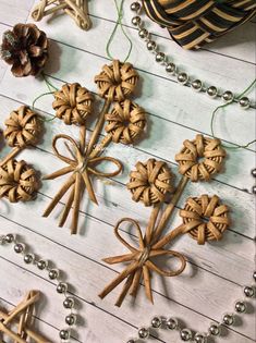 several wooden ornaments are arranged on a white wood table with beads and pineconi