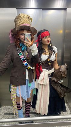 two women dressed up as pirates taking a selfie in front of an escalator