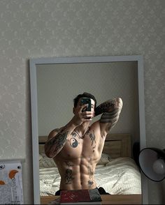 a shirtless man taking a selfie in front of a mirror with his camera