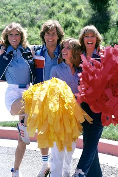 the cast of grease pose for a photo in front of an outdoor area with trees and bushes behind them