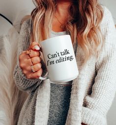 a woman holding a coffee mug with the words meant mocks printed on it, in front of her