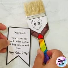 a person holding a paintbrush with a card attached to it that says, dear dad you paint my world with colors if happiness and love