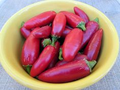 a yellow bowl filled with red peppers on top of a table