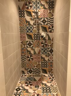 a tiled shower stall in a bathroom with multicolored tiles on the walls and floor