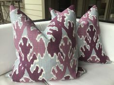 two purple and white pillows sitting on top of a couch