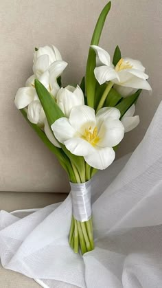 a bouquet of white flowers sitting on top of a table next to a white cloth