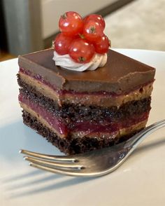 a piece of cake on a plate with a fork next to it and a cherry on top