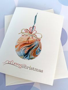 two christmas cards with an ornament hanging from it's side on top of each other