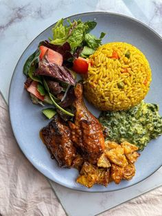 a white plate topped with meat, rice and veggies next to a salad