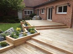 a wooden deck with steps leading up to it and flowers growing in the planters