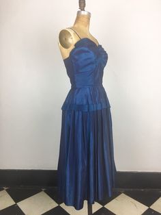 "1950s iridescent blue taffeta 2 piece has a matching jacket and dress. The jacket is open style with shawl collar and cuffed sleeves. The dress has stiff pleated trim around the bust and hips, and an extra layer of gathering around the bust. The skirt is pleated around the waist, and there's a metal zipper in the back for entry. Condition Excellent overall. The strap thread is strained where they connect to the dress- they may just need to be reinforced with a machine. There is a cut in the hem 1950s Blue Evening Dress, 1950s Style Blue Evening Dress, Blue 1950s Evening Dress, 2 Piece Formal Dress, 2 Piece Formal Dresses, White Peasant Blouse, Taffeta Fabric, Fabric Ideas, Iridescent Blue