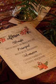 a menu is sitting on a table next to a vase filled with flowers and greenery