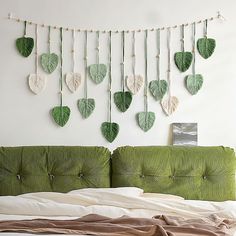 a bed with a green headboard and hanging leaves on the wall next to it