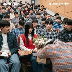 a group of people sitting next to each other in front of a staircase with flowers