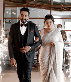 a man and woman dressed in formal wear walking down the aisle with sparklers behind them