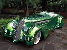 a green car is parked in front of some trees