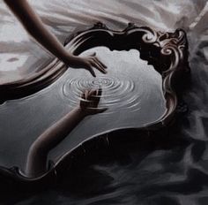 a woman's reflection in the water with her arm extended out to touch it