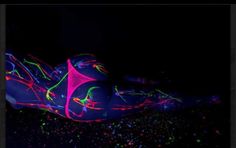 a pair of neon shoes is laying on the ground in front of a black background