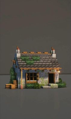 a small house made out of legos on top of a gray surface with trees and bushes around it