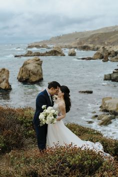 a bride and groom kissing in front of the ocean on their wedding day at point lo state park