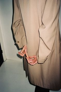 a person in a trench coat is holding their hand on the back of his jacket