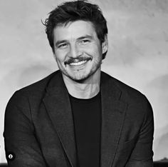 a black and white photo of a man with a smile on his face, wearing a suit