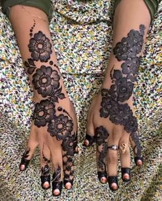 two hands with henna tattoos on them, one is black and the other has white flowers