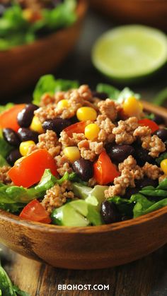 a salad in a wooden bowl with black beans, tomatoes, corn and lettuce