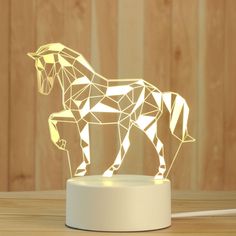 a horse shaped lamp sitting on top of a wooden table next to a white light