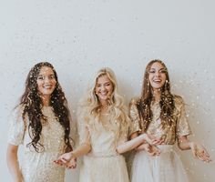 three beautiful women standing next to each other with confetti falling from their mouths