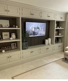 a living room with white furniture and a flat screen tv mounted on the wall above it