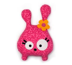 a pink stuffed animal with a flower on it's head and eyes, sitting in front of a white background