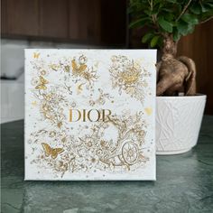 a card with the word dior on it sitting next to a potted plant