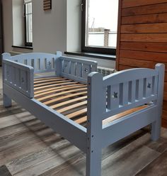 a blue bed frame sitting on top of a hard wood floor next to a window