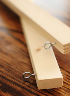 a piece of wood with a metal hook attached to it on a wooden table top