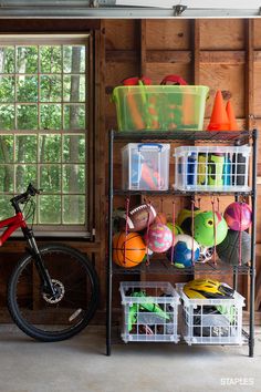 a bicycle is parked next to a rack with balls and other items on it in front of a window