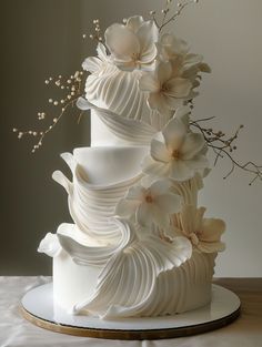 a three tiered white wedding cake with flowers on top